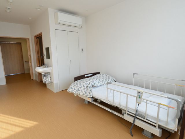 清潔感ある居室 居室 広々とした居室は、採光も豊かで快適な日常生活を支えます。手すり付きベッドや洗面設備も整っており、利用者の安全と便利を重視した設計です。
