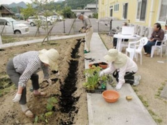 利用者と共に庭仕事をするスタッフ