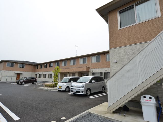 茶色い建物の外観 外観 広々とした駐車スペースが確保された、清潔感のある建物です。ゆったりとした環境で、職員としての新しいスタートを切れます。