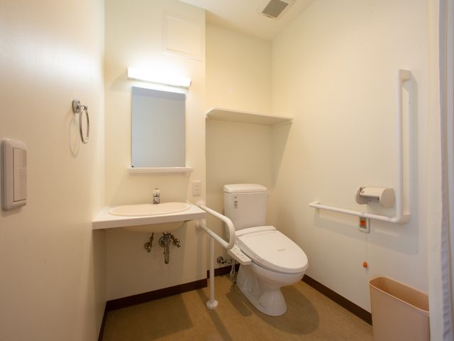 バリアフリーのトイレ設備 トイレ 手すり付きの清潔なトイレ空間です。利用者の方々が安心してご使用いただける配慮がされています。
