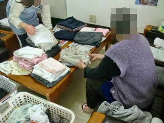 衣類を折る利用者と職員