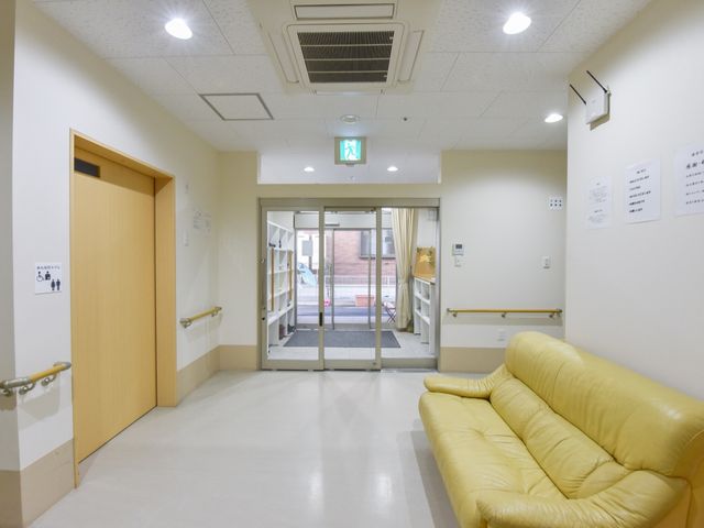 廊下とエントランスの様子 ロビー 広々として明るいエントランスです。黄色いソファが設置され、ゆったりとお過ごしいただける空間となっております。