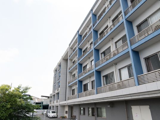 青いアクセントのある居室外観