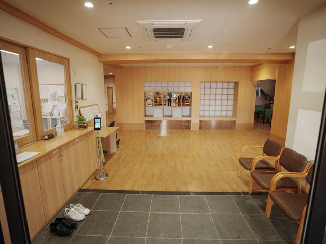 明るく開放的な受付エリア 玄関 木の温もりあふれる広々とした受付エリアで、利用者様とのコミュニケーションが図れる環境が整っています。