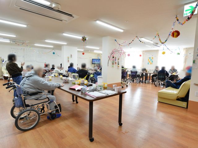 共有リビングエリア リビング・ダイニング 賑やかな雰囲気の食堂です。利用者の皆さまがくつろぐ姿があり、明るく開放感のある場所として設計されています。