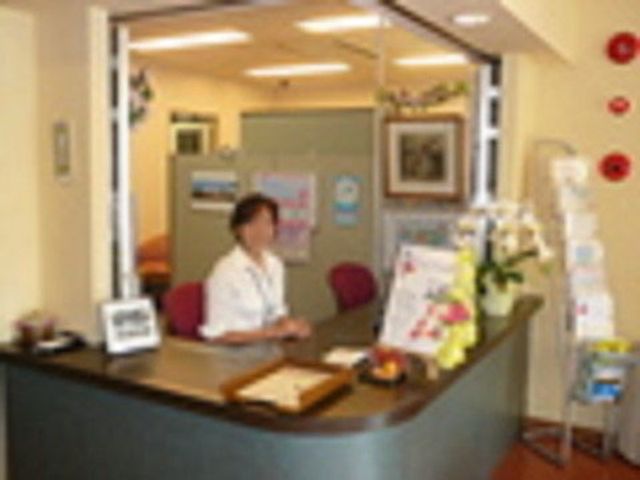受付の女性とフロント 館内環境 明るく清潔感のあるフロントで、笑顔のスタッフが訪問者を迎えています。案内やサポートも丁寧に行われるため、安心して業務を始められます。