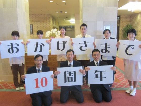 笑顔のスタッフと記念板