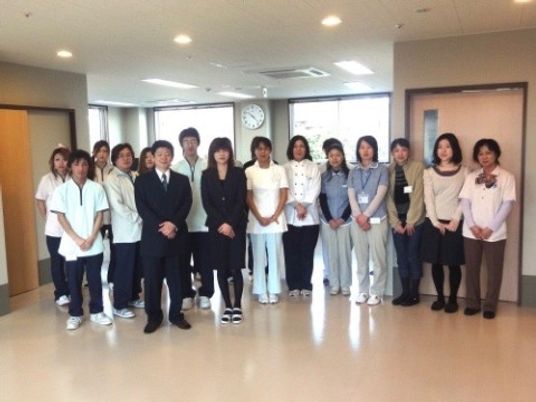 壁に掛かる時計の下のチーム写真