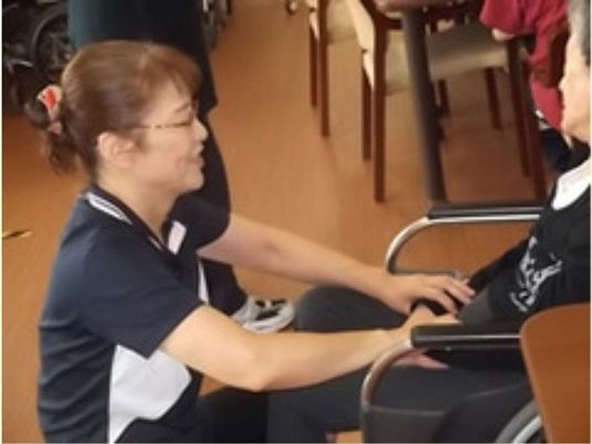 スタッフが椅子の方に微笑む様子