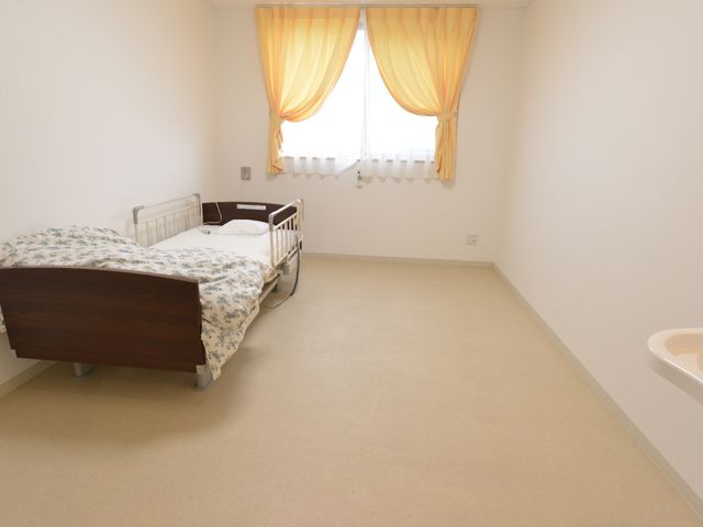 広々とした明るい居室 居室 ゆとりのある居室で、落ち着いた色合いのベッドが備え付けられ、穏やかな時間を過ごせます。窓から自然光が差し込み、温もりを感じる空間です。