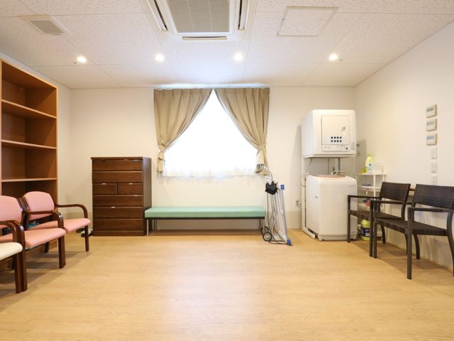 居心地の良い休憩室 スライドショー 落ち着いた色合いで整えられた休憩室です。待合用の椅子や生活必需品が配置され、機能的な空間となっています。