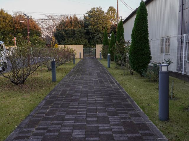 緑豊かなアプローチ道 玄関 きちんと手入れされた植栽と、整備されたアプローチが迎えてくれます。働く場所としての心地よさが感じられる環境です。