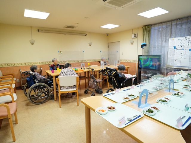 居室の共有スペース 共有スペース テーブルを囲んで穏やかな時間を過ごしている様子です。食事の準備が整い、コミュニケーションも活発に行われています。