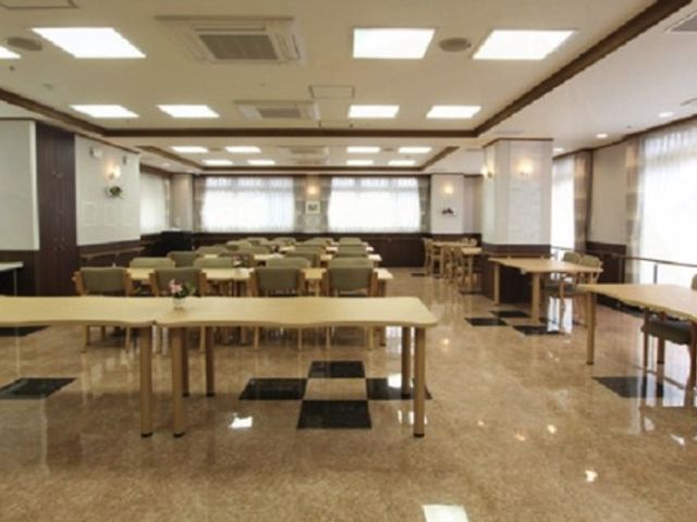 広々とした明るいダイニング 食堂 ゆったりと配置されたテーブルとイスが並び、落ち着いた雰囲気のダイニングルームです。こちらで職員や利用者様が食事やコミュニケーションをお楽しみになっています。