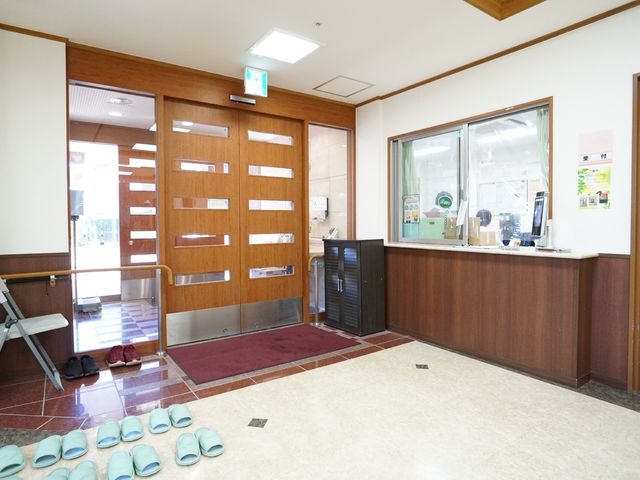 温かみのあるエントランス 玄関 明るい光が差し込む受付スペース。スタッフの対応も見え、安心感が伝わります。