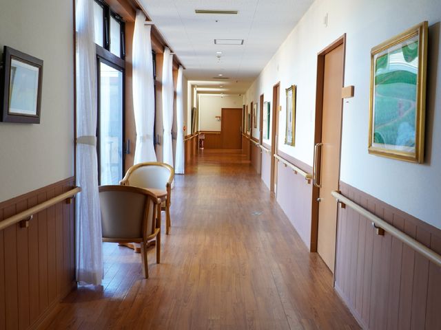 明るい廊下の風景 廊下 手すり付きで安全な通路が広がり、壁には絵画が飾られ心地よい。