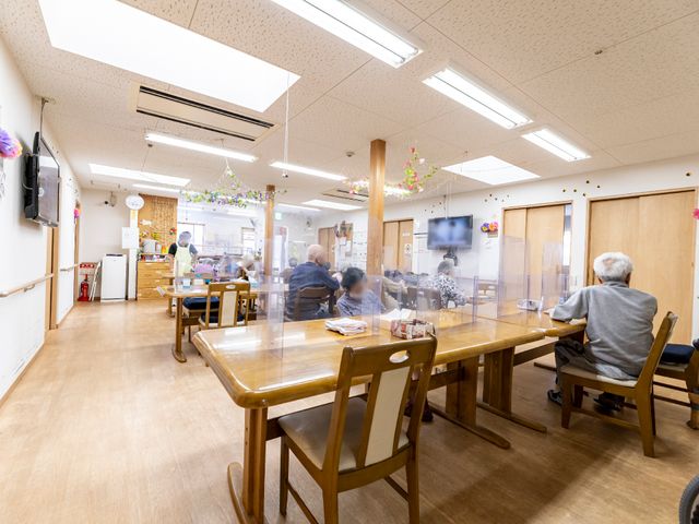 明るい居心地の良い食堂 共有スペース 広々と開放的な空間で、利用者の方が食事や交流を楽しんでいる様子が伺えます。スタッフも丁寧に対応しており、安心して生活ができる環境が整っています。