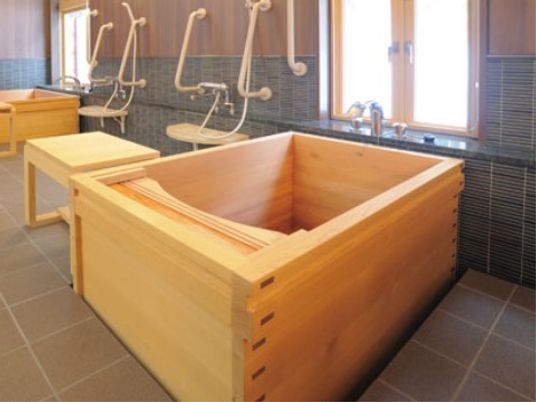 浴室にはヒノキ風呂をご用意している。そばにシャワーベンチが置かれ、足腰に不安のある方も安全に入浴できるようになっている。