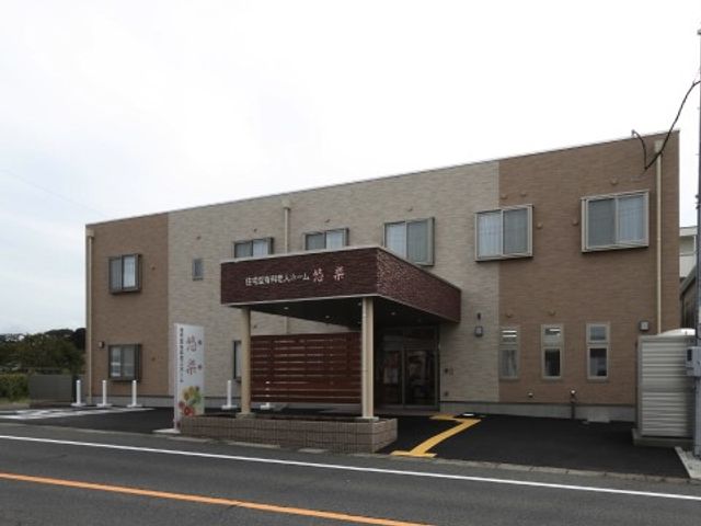 外観の建物とエントランス 外観 温かみのある色合いの建物で、入口には親しみやすいデザインの看板があります。