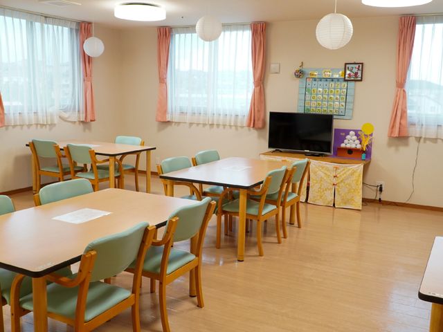 温かみのある共有スペース 共有スペース 天井のライトが優しく照らす広々とした食堂です。テーブルの配置もゆったりとしており、共有する時間を快適に過ごせます。