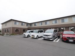 茶色い外壁の建物と駐車場