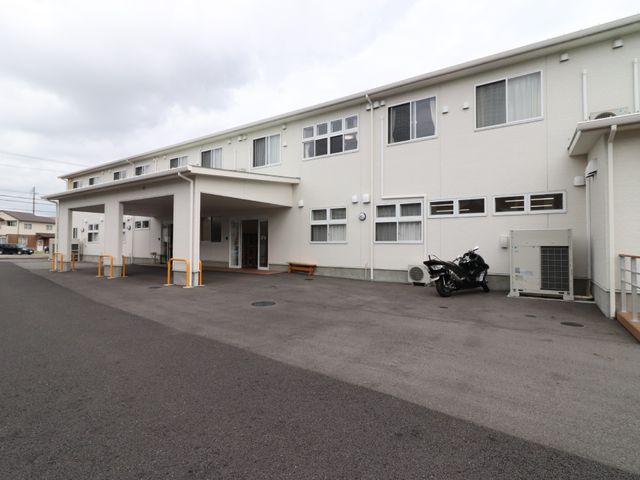 白い建物のエントランス 外観 広々とした入口があり、明るい外観が印象的です。心地よい空間でお迎えする準備ができています。
