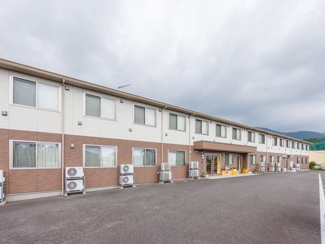 施設外観 外観   白と茶色の外壁が印象的な、落ち着いた雰囲気の建物です。広い駐車スペースがあり、出入りしやすそうです。