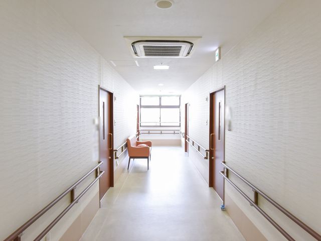 明るい広々とした廊下 通路 手すりが取り付けられた安全な通路で、どなたでも安心して歩行できる設計です。窓からは自然光が差し込み、開放感ある雰囲気を演出しています。