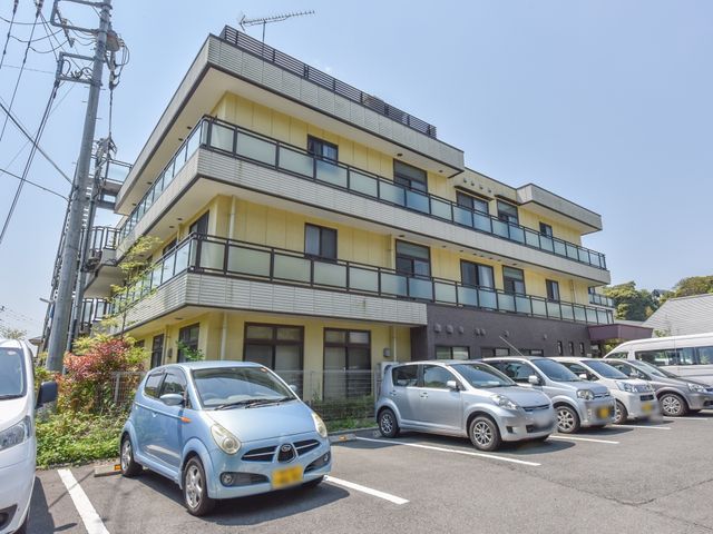 黄色い外壁の建物外観 外観 日当たりの良い落ち着いた色合いの建物です。駐車場も広く、ご来訪の際は便利にご利用いただけます。
