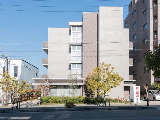 現代的な建物の外観 外観  洗練されたデザインの外壁が特徴の建物です。落ち着いた色合いと緑の植栽が、優しい雰囲気を醸し出しています。