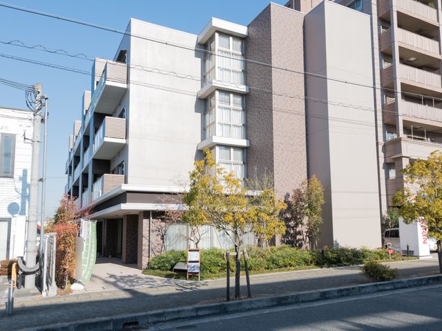 明るい外観の施設入口 外観  日差しが心地よいエントランスは、ご来訪の際の第一印象を決める大切な空間です。訪れる方々を暖かく迎え入れます。