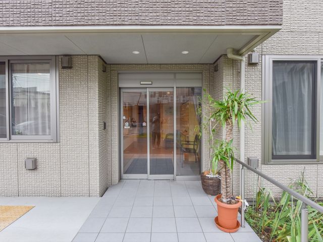 玄関の自動ドアと植物 玄関 手入れの行き届いた植物が迎えるエントランスは、透明な自動ドアで開放的な印象を与え、訪れる方に安らぎを提供します。