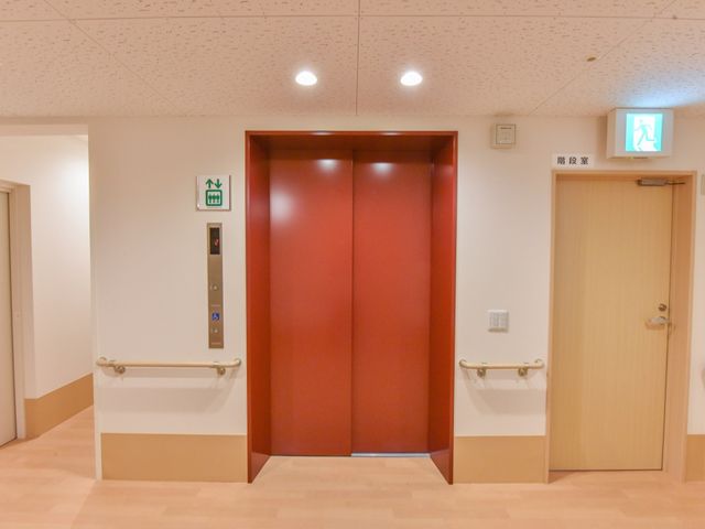 赤茶色のきれいなエレベーター エレベーター 手すりが設置されたエレベーター周辺です。この設備は来訪者の利便性を考慮したデザインになっており、快適にご利用いただけます。