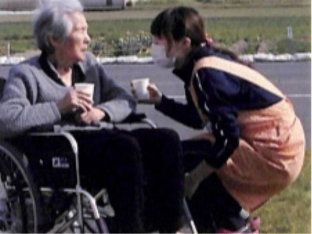 笑顔で接する職員の姿 中庭 職員が利用者と共にふれあい、笑顔で対話をしている光景です。温かなケアを実践できる職場です。