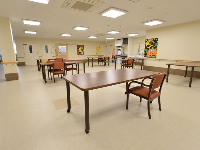 清潔で広々とした食堂 リビング1 ゆとりのある広々とした食堂は、落ち着いた木目調のテーブルが配置され、心地よい滞在時間を過ごせる設計です。壁にはカラフルなアートが飾られ、明るい雰囲気が演出されています。
