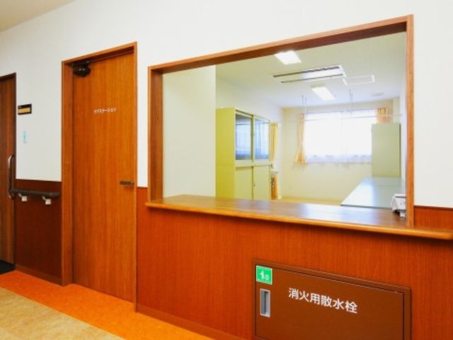 受付カウンターの明るい空間 介護職員室 見通しの良いフロントは温かみのある木目調で、訪れる方を明るくお迎えします。対応スペースも広く、待合もゆとりを持ってお使いいただけます。