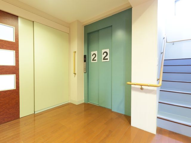 清潔な廊下の角 エレベーター きれいに保たれた角に2つの扉があります。手すりも設置され、安全な移動が考えられています。