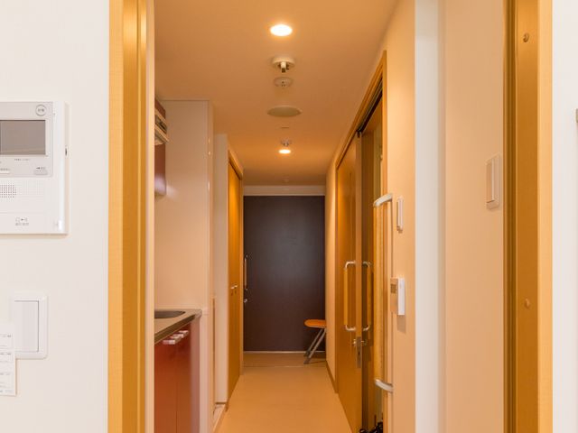 廊下の明るい空間 部屋 温かみのある照明が印象的な通路です。清潔感のある空間が広がっています。