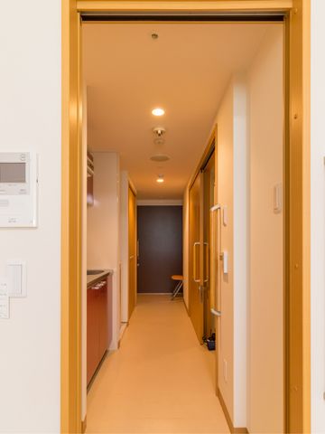 廊下の明るい空間 部屋 温かみのある照明が印象的な通路です。清潔感のある空間が広がっています。