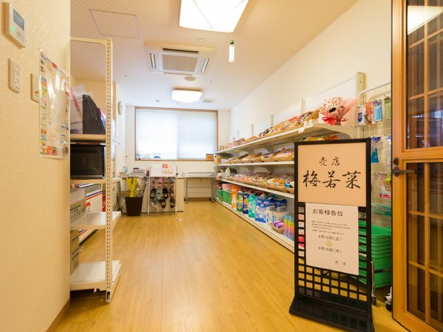 商品が整然と並ぶ多目的室 売店 日用品からお菓子まで、生活に必要なものをそろえた空間です。明るい光が差し込む明るい雰囲気が特徴です。