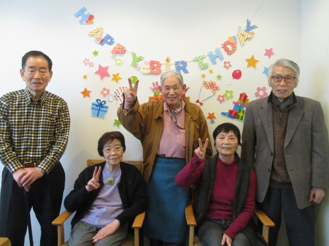 お祝いの背景と笑顔の集合 お誕生会 明るい背景の前で、ピースサインをするなどしてポーズを取る皆さんの笑顔が印象的です。ここでの暮らしは、楽しい時間を共に過ごせる充実したものになるでしょう。