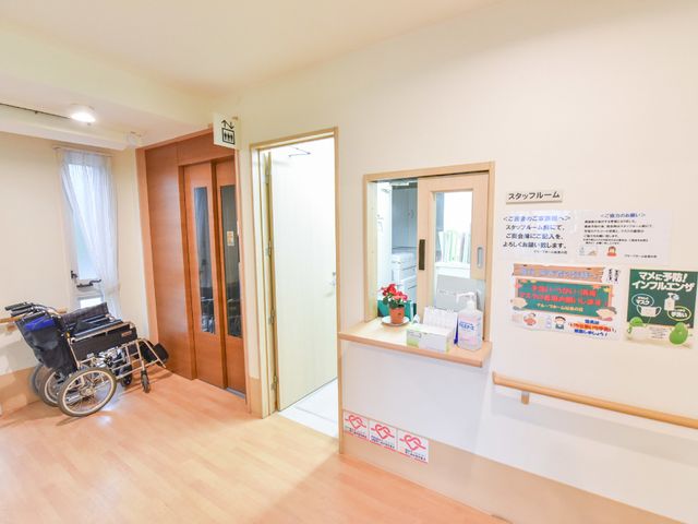 明るい受付と廊下の様子 エレベーターホール 開放的で清潔な待ち受けエリアです。手すりが整った廊下は、安心して歩けるよう配慮されています。