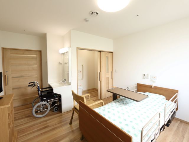ゆとりある明るい居室 居室 広々とした居室は、日差しが心地よく差し込む設計になっており、ベッド横の椅子でゆったりとくつろげる空間です。