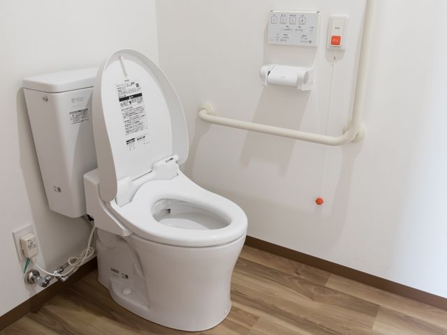 バリアフリートイレ トイレ 安全ハンドル付きのモダンなトイレで、緊急時にも安心してご使用いただける設計になっています。サポートが必要な方も自立支援を促します。