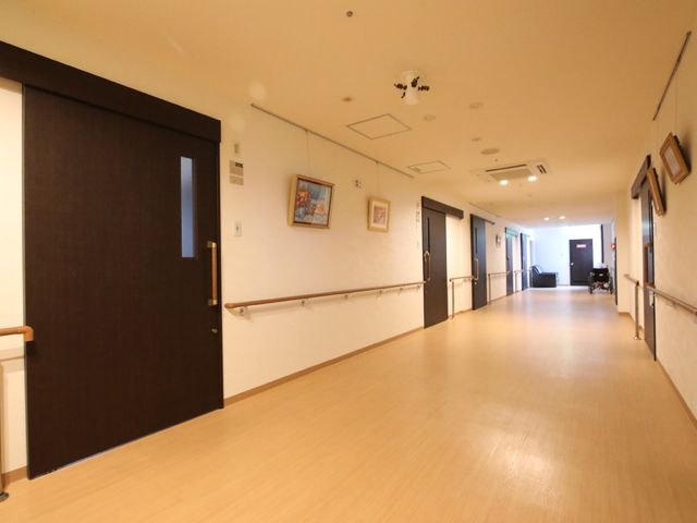 ゆったりとした廊下 廊下 手すり付きの廊下は、広々として歩きやすい作りです。明るく清潔感のある環境で、利用者の方々の生活をサポートしています。