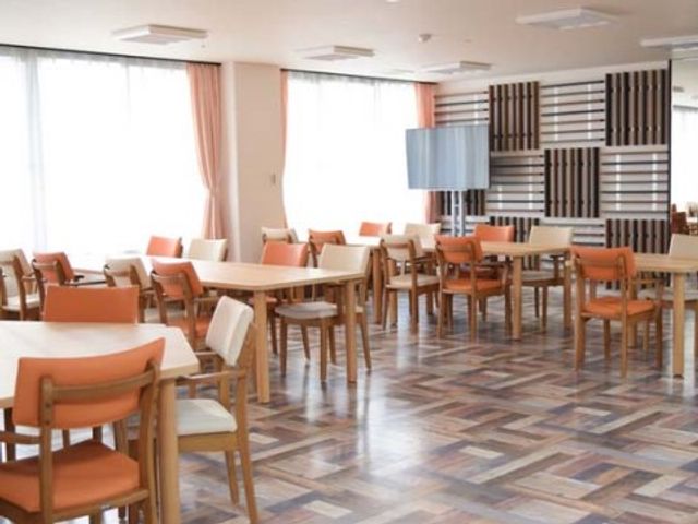 明るい食堂の内観 食堂 ゆとりある空間が広がる明るい食堂です。各テーブルにはオレンジ色の椅子が配置され、温かみのある雰囲気を演出しています。
