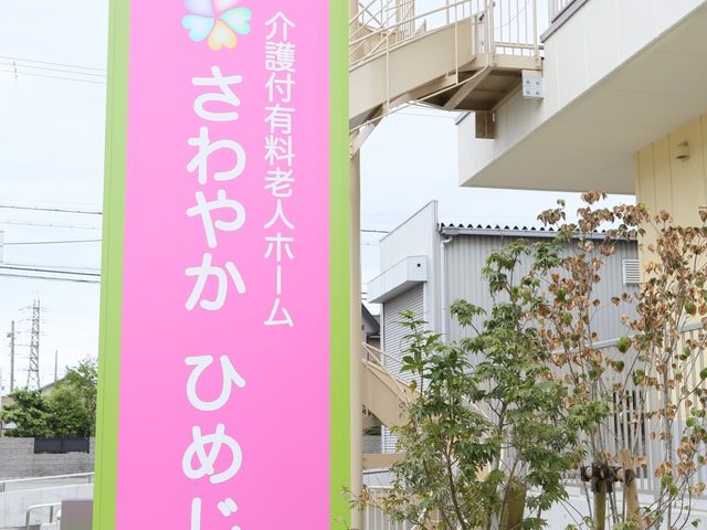 緑色看板と建物 看板 色鮮やかな看板が目印の明るい雰囲気の場所です。訪れる方々を暖かく迎え入れるデザインが特徴です。