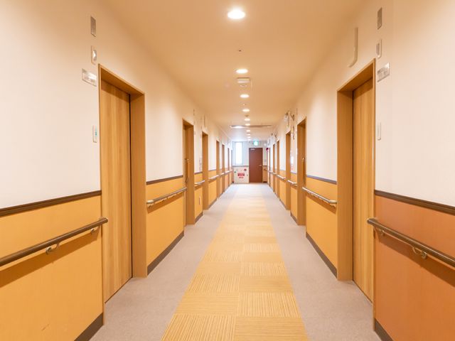 清潔な廊下の様子 廊下 手すり完備の廊下は清潔感があり、明るく落ち着いた雰囲気です。ゆったりした空間で日々の業務に取り組みやすい環境を提供しています。