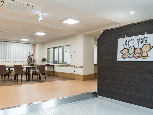 広々とした食堂空間 玄関ホール 明るく広々とした食堂で、いつでもお食事やくつろぎの時を過ごせます。壁には心温まる掲示物が飾られ、温かな雰囲気が漂います。