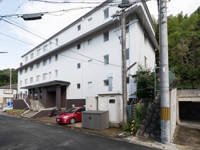 白い壁の建物外観 外観 清潔感のある白い壁が目を引く建物。エントランスには階段とスロープがあり、バリアフリーへの配慮が見てとれます。